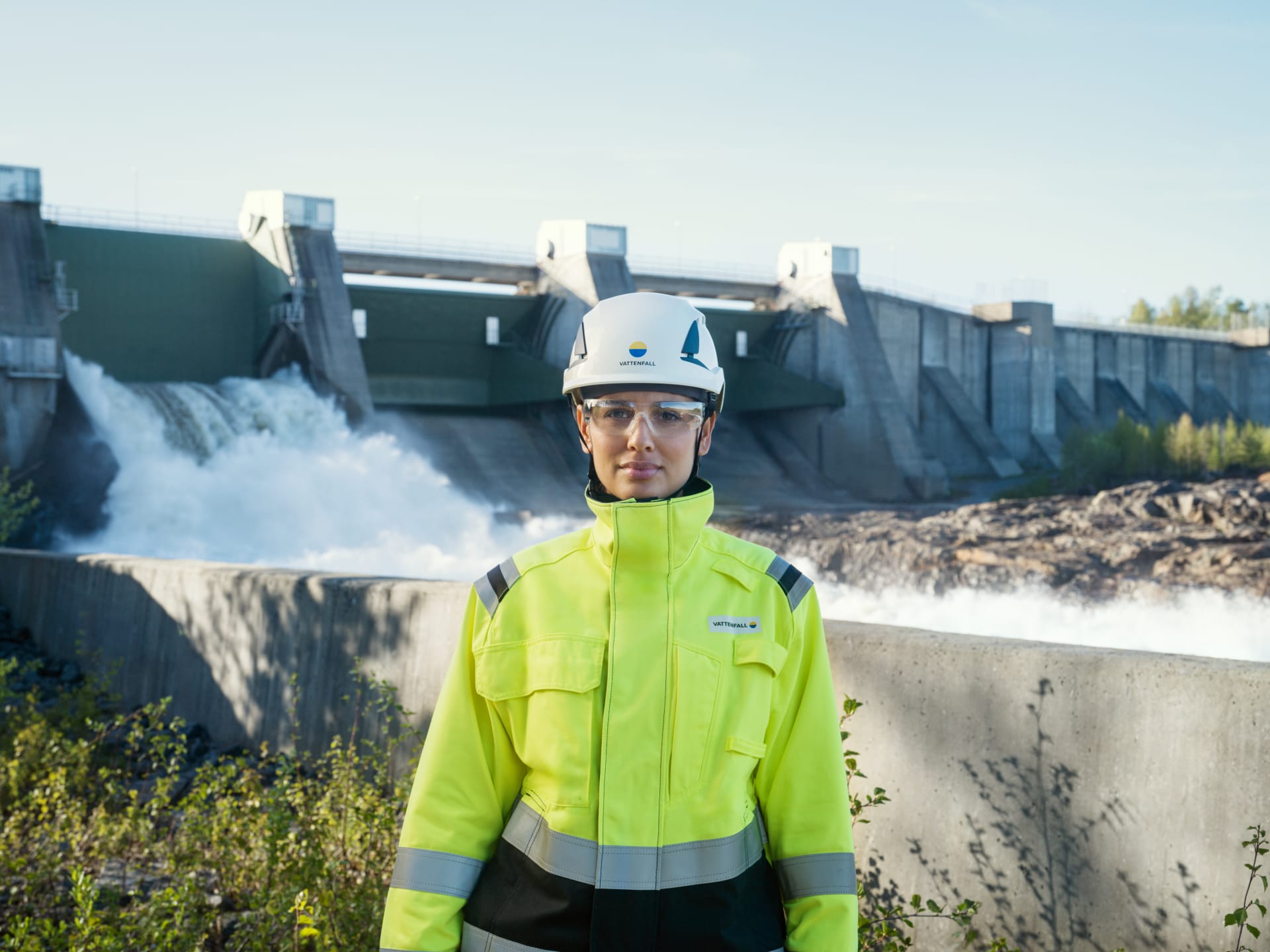Woman Employee PPE in front of Hydro plant water flowing